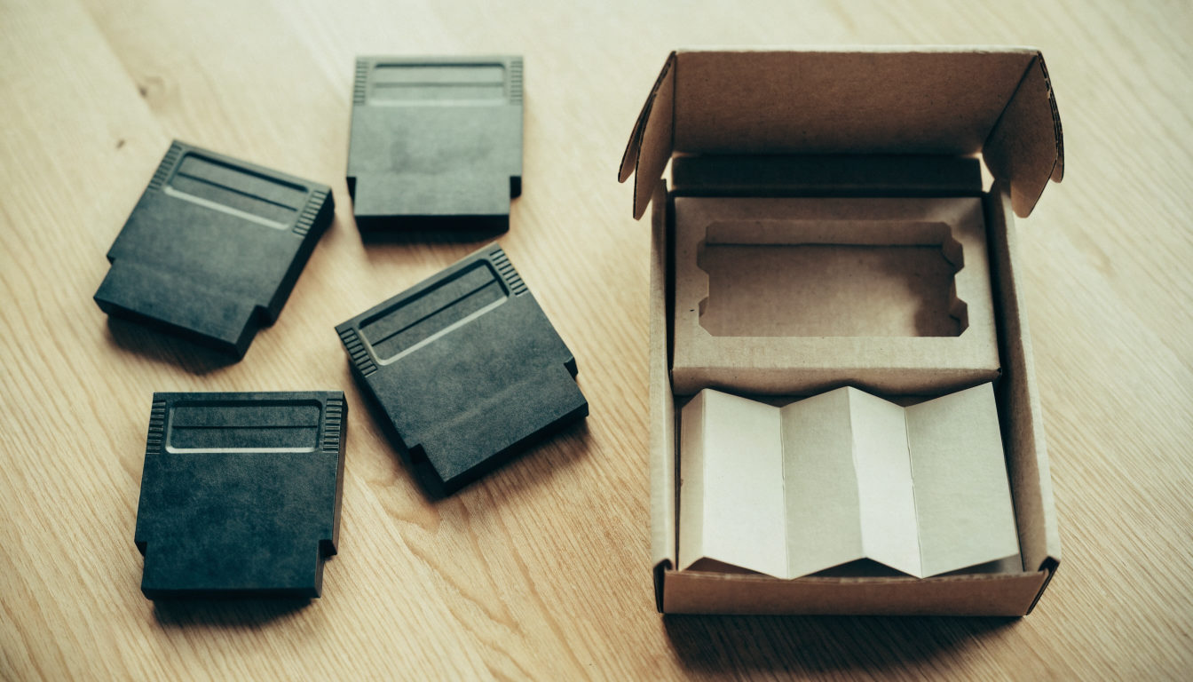 Mehrere Spielmodule und eine geöffnete Pappbox mit Anleitung, sortiert auf einem Holztisch